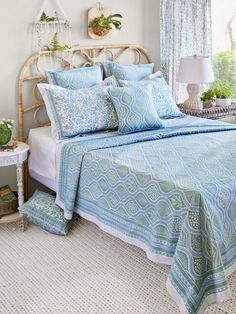 a bed with blue and white bedspread in a bedroom next to a window