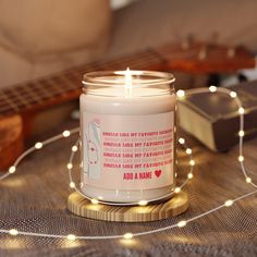 a white candle sitting on top of a wooden table next to a string of lights