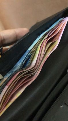 a person holding a wallet full of money in their left hand and the other half open