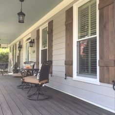 a porch with chairs and lamps on the side of it next to a door that has shutters