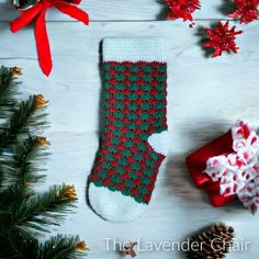 a christmas stocking with red and green designs next to pine cones, candy canes and other holiday decorations