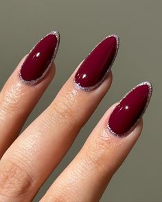 Almond nails in a rich, deep red shade are outlined with a fine layer of silver glitter. This look combines sophistication with a touch of sparkle, perfect for holiday parties. Ideal for those seeking a bold winter almond style. Acrylic Winter Nails, Summer Lipstick Colors, Red And Silver Nails, Winter Nails Ideas, Summer Lipstick, Red Nails Glitter, Glitter Accent Nails, Nail Art Photos, Winter Nails Acrylic