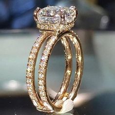 two gold rings with diamonds on them sitting on top of a glass table in front of a mirror