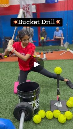 a woman is hitting tennis balls with a racket and some buckets on the ground