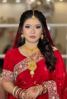 a woman wearing a red sari and gold jewelry