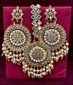 an elaborate necklace and earring set on display in a red velvet box with gold trimming