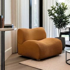 an orange chair sitting in front of a window next to a table with a potted plant on it