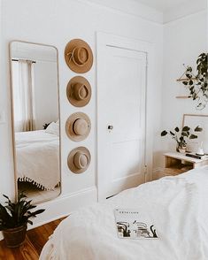 a bedroom with hats on the wall and a bed in front of a large mirror