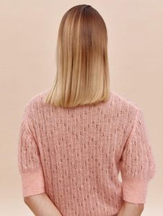 a woman with blonde hair wearing a pink sweater