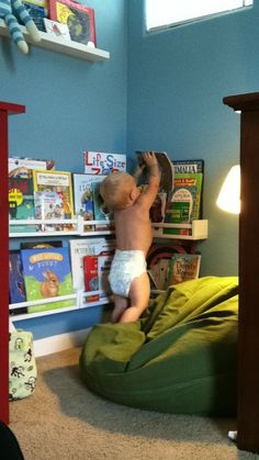 a baby in diapers is playing on a bean bag chair and bookshelf