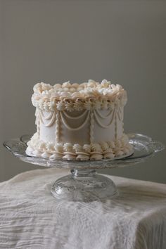 a white cake sitting on top of a glass plate