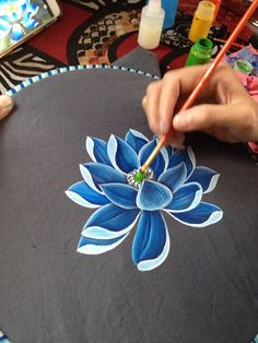 someone is painting a flower on a round table