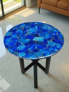 a blue table sitting on top of a white floor next to a brown couch in a living room