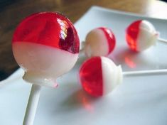 three lollipops on a white plate with red and white candies in them