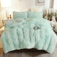 a bed covered in a light green fluffy comforter