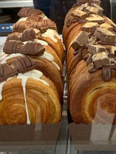 two loaves of bread with chocolate and cream toppings on display in a bakery