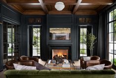 a living room filled with furniture and a fire place in the middle of two windows