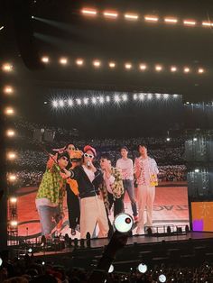 a group of people standing on top of a stage in front of a large screen