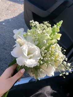 a person holding a bouquet of flowers in their hand next to a car door handle