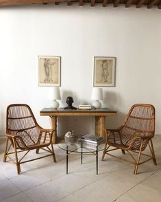 two wicker chairs sitting next to a table with vases on top of it