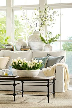 a living room filled with lots of furniture and flowers on top of a coffee table