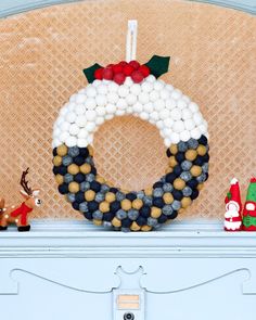 a christmas wreath on top of a mantle next to other holiday decorations and decorating items