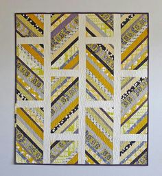 a quilted wall hanging on the wall with yellow and blue strips in it's center