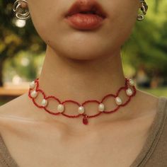 a close up of a woman wearing a necklace with pearls and bells on it's neck