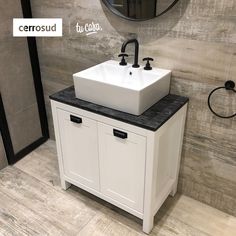 a white sink sitting under a mirror next to a wall mounted faucet in a bathroom