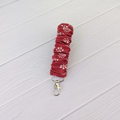 a red umbrella with white flowers on it is tied to a hook in the snow