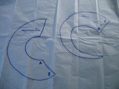 two pieces of white paper with blue lines drawn on them, and one piece of scissors in the middle