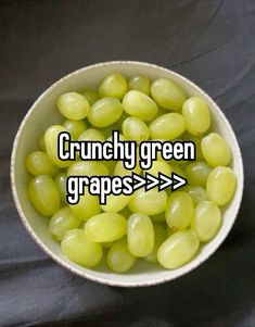 a white bowl filled with grapes sitting on top of a black tablecloth covered floor