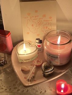 a heart shaped tray with two candles and some other items on it next to a valentine's day card