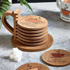 wooden coasters stacked on top of each other with tea cups and saucers next to them