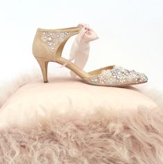 a pair of women's shoes with bows and pearls on the heels are sitting on a fur pillow