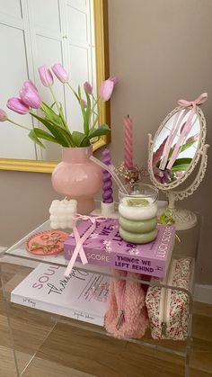 a glass table topped with pink flowers next to a mirror and other items on top of it