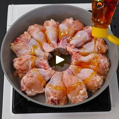 chicken cooking in a skillet on top of the stove with a glass next to it