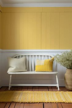 a white bench sitting next to a potted plant on top of a wooden floor