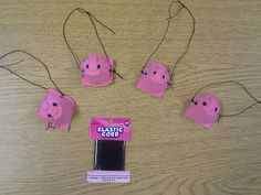 three pink pig ornaments on a table with some string attached to it's ears