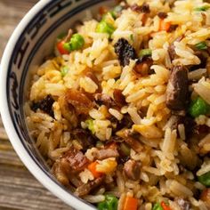 a bowl filled with rice and vegetables on top of a wooden table