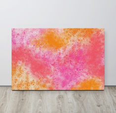 an orange and pink painting on a white wall next to a wooden floor with a wood floor