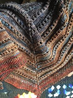 a close up of a knitted blanket on the floor with crochet work