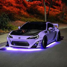 a purple sports car with blue lights on it's hood is driving down the street