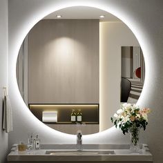 a bathroom sink with a mirror above it and flowers in the vase on the counter