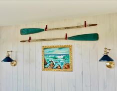 three canoes mounted to the wall above a painting and two lamps on either side