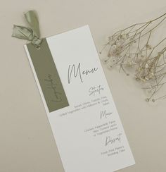 a menu card sitting on top of a table next to some flowers and a ribbon