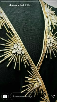 the back of a woman's black dress with gold trimmings and jewels