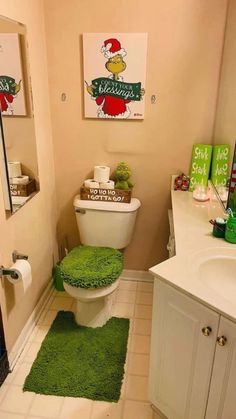 a bathroom with green rugs and pictures on the wall above the toilet, along with other accessories