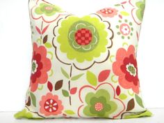 a pillow that is on top of a white table with a red and green flower pattern