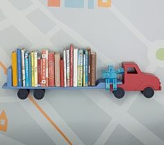 a toy truck with books on it is sitting in front of a wall